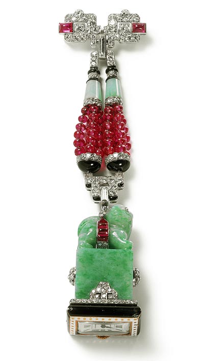 - <b>Montre-broche cachet</b> - Cartier Paris, 1929 - Or, platine, diamants, rubis, jade, onyx, émail. La montre enchâssée dans un cachet de jade –Chine, XIX<sup>e</sup> siècle, représentant un lion bouddhique sur un socle. Collection Cartier - Nick Welsh, Collection Cartier © Cartier